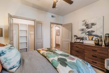 A bedroom with a bed, dresser, and ceiling fan.